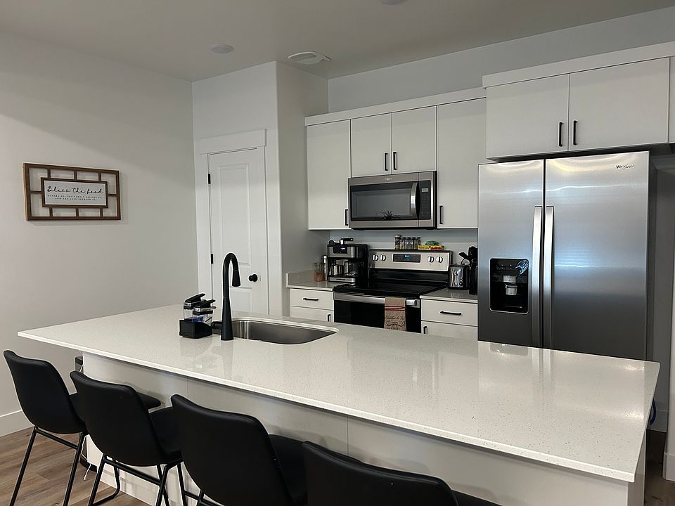 Kitchen includes stove, refrigerator and bar stools.