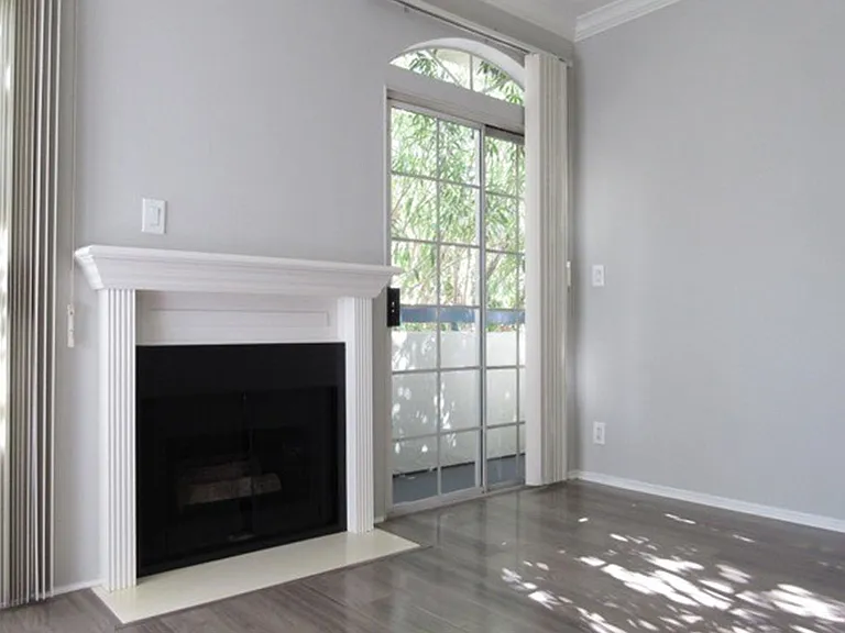 Fireplace with overhanging mantle and large windows with patio access.