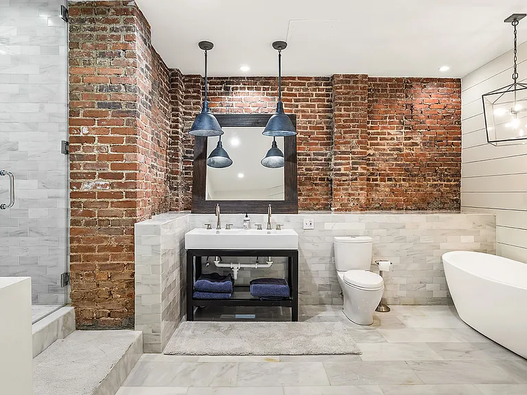 Spa like main bathroom with marble, custom lighting and exposed brick wall. Features large steam shower and soaking tub.