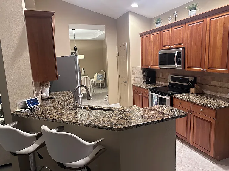 Fully furnished kitchen with counter seating and two additional dining areas.