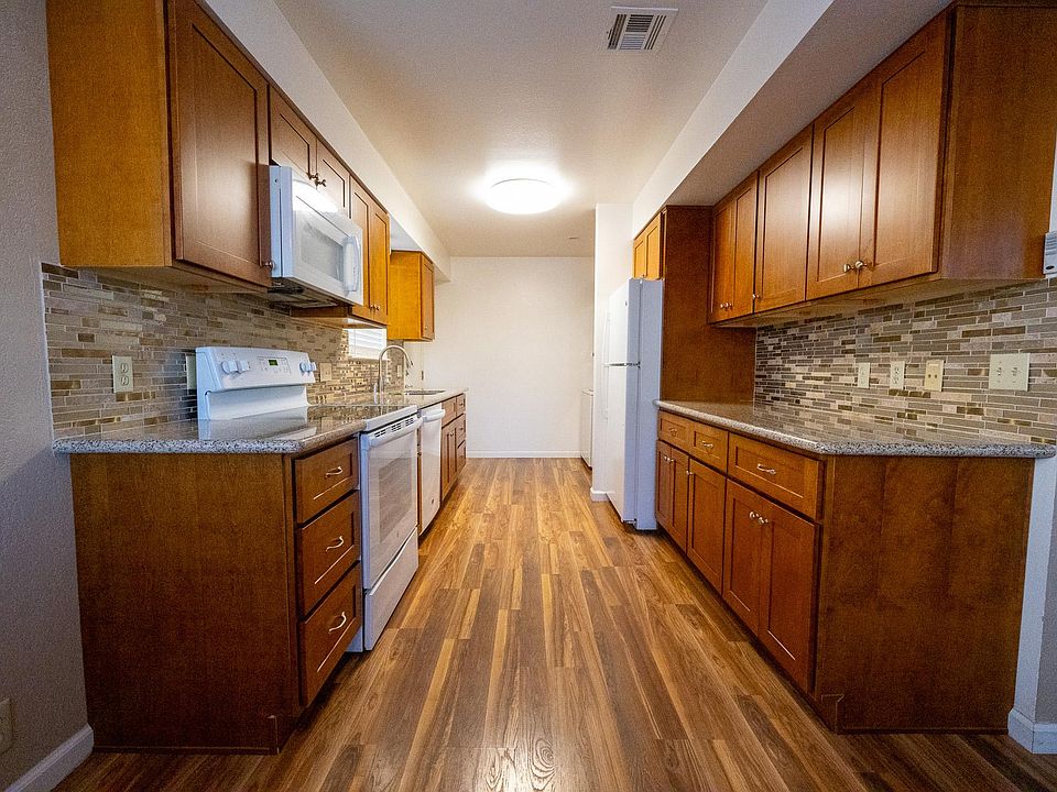 Kitchen with granite countertops, range, dishwasher, microwave, & refrigerator.