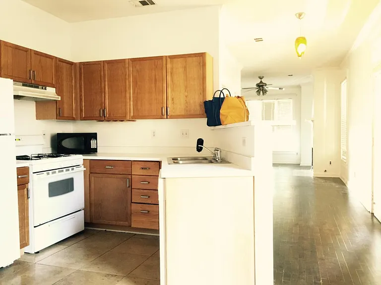 Unoccupied view of the Kitchen, with front hallway leading towards the living room.