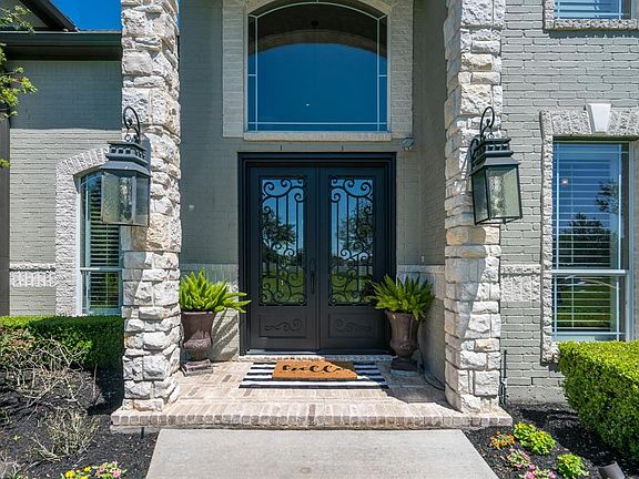 An arched two-story front porch welcomes you to the iron double doors, making a grand statement!