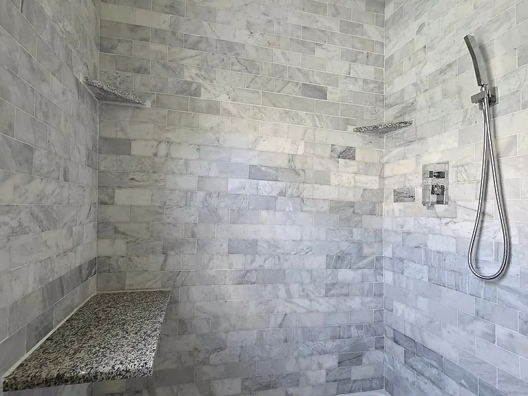 Custom Turkish marble. Large rain shower and wand. Built in shelves and bench.