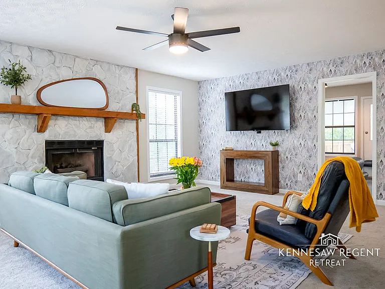 This newly designed living room is a perfect blend of style and comfort with carefully curated mid-century modern furniture. A large 65-inch television provides ample entertainment, while plush seating invite relaxation.