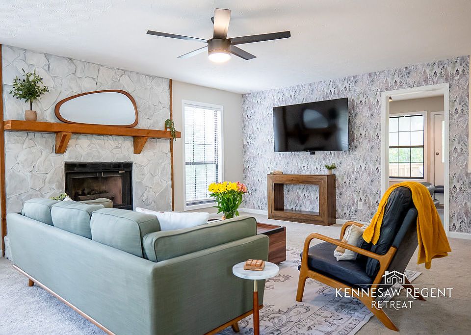 This newly designed living room is a perfect blend of style and comfort with carefully curated mid-century modern furniture. A large 65-inch television provides ample entertainment, while plush seating invite relaxation.
