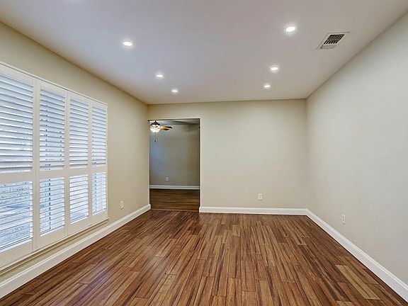 Large formal living room looks to the front yard with quality laminate floors, plantation shutters and recessed lighting.