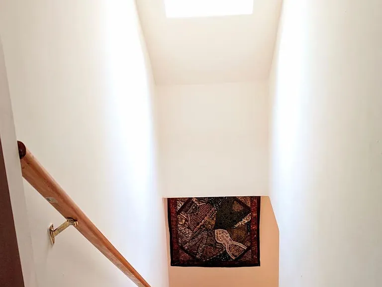 The upstairs staircase is bright under a skylight.