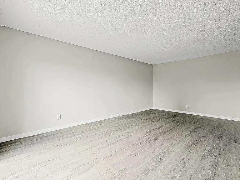 Bright and spacious empty room featuring elegant wooden flooring and large windows, perfect for customization and natural light.