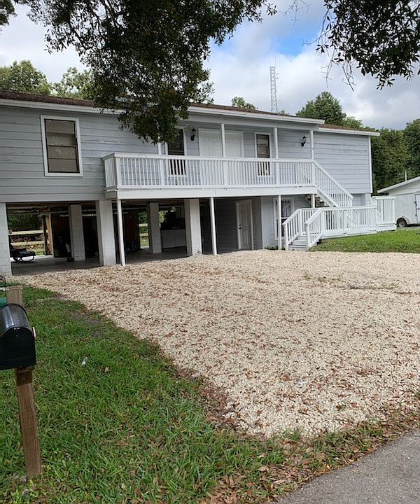 Front View. Stairs and balcony to double door entry to living room 2nd floor of house. Side stairs and rear balcony for entertaining. Overlooks lots of trees. Tiki bar.