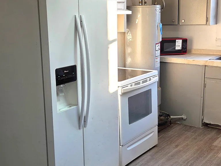Compact kitchen with full-size refrigerator, range, and ample cabinetry plus durable flooring for easy everyday use.
