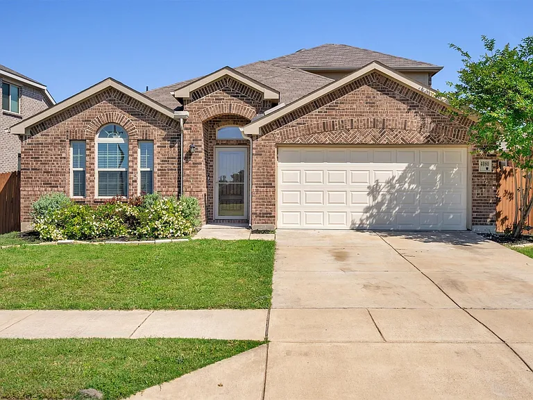 Brick facade residence featuring an arched entryway and a two-car garage
