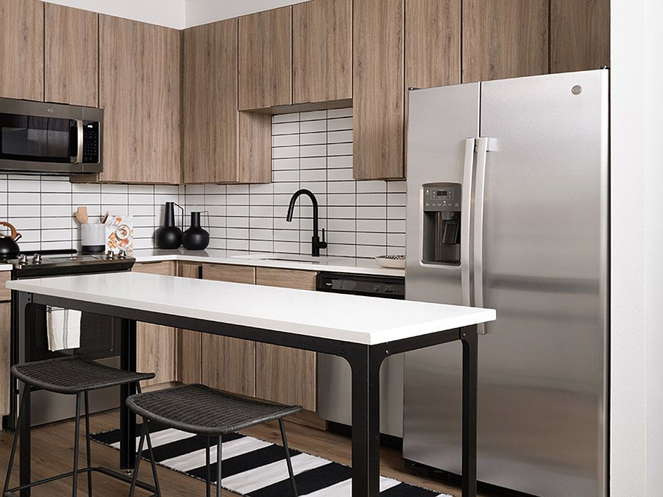 Apartment kitchen with stainless steel appliances, quartz countertops and wood-style flooring.