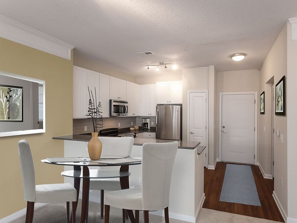 Dining area and kitchen with quartz stone countertop, white cabinetry, tile backsplash, stainless steel appliances and hard surface flooring