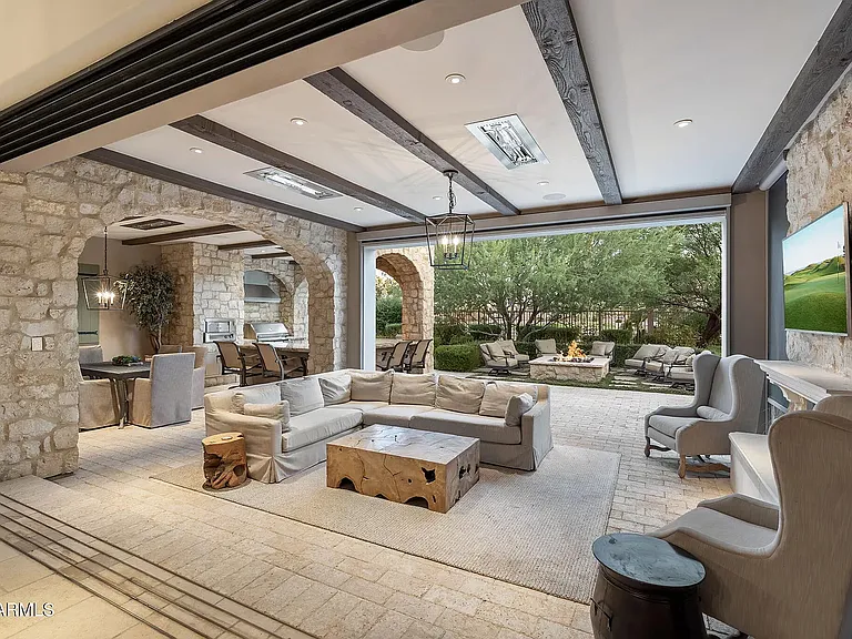 Spacious covered patio designed for entertaining, featuring a fireplace, lounge seating, and direct access to the outdoor oasis.