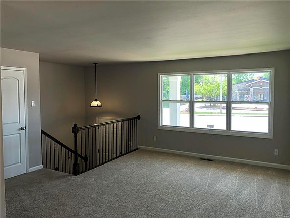 Living room with new carpet and pad.  Open iron-rail spindles leading to entry foyer and finished lower level.