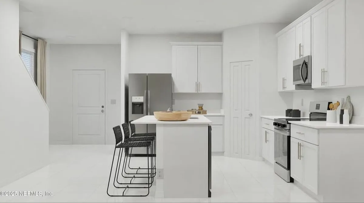 Bright open-concept kitchen with white cabinets, quartz countertops, stainless steel appliances, and a center island. - 3964 Mid Century St