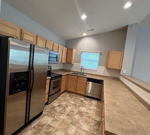 Bright kitchen with stainless steel appliances and deep sink with upgraded faucet.