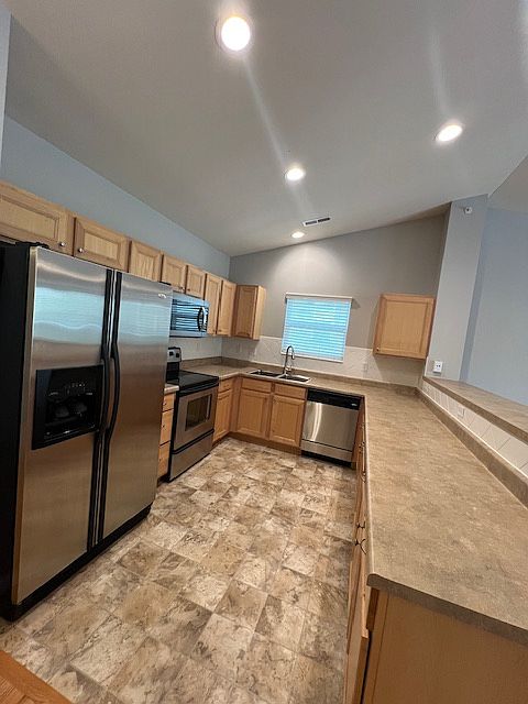 Bright kitchen with stainless steel appliances and deep sink with upgraded faucet.