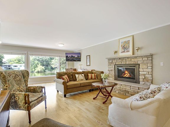 The living room features a gas fireplace, hardwood floors and lovely views out picture windows overlooking small lake.