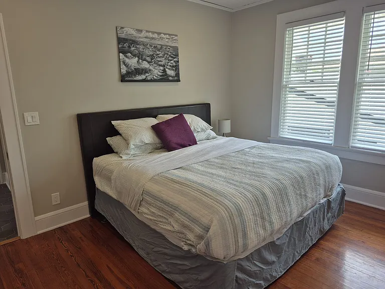 Bedroom is spacious with king bed, bedside table and lamp.