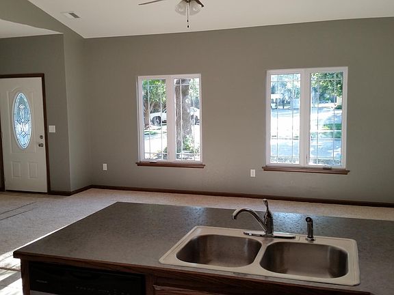 From kitchen facing front entry and living room. Coat closet with shelves, front door.