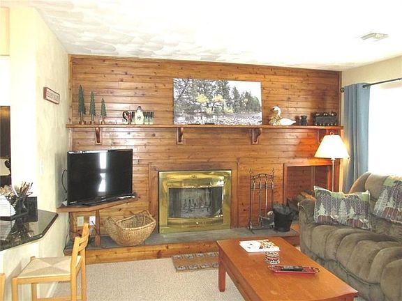 Knotty pine wall highlights the wood burning fireplace. Kitchen is off to the left and ski slopes are to the right!