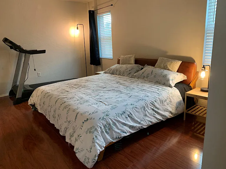 The master bedroom with night stands and a treadmill.