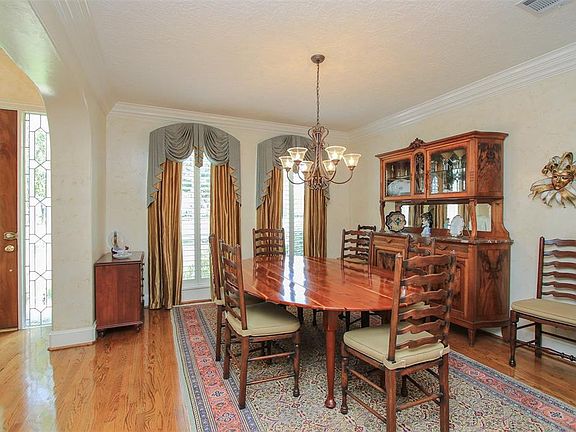 The formal dining room has plantation shutter, crown molding and a gleaming wood floor.