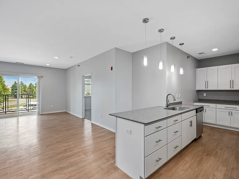 Modern open-concept apartment with sleek kitchen, bright living area, and large windows offering lush views. Modern open-concept apartment with sleek kitchen, bright living area, and large windows offering lush views.