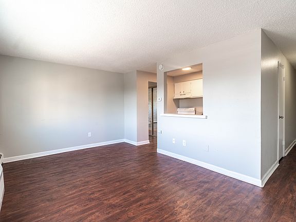 Bright and airy living space with modern hardwood floors leading to a cozy kitchen area.