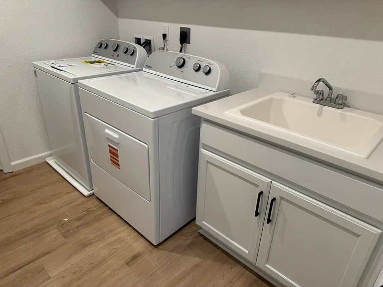 New washer and dryer with sink in laundry room with walk-in linen closet