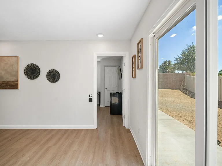 Open flex room with wood-look flooring, recessed lighting, and large sliding doors leading to a fenced outdoor area.