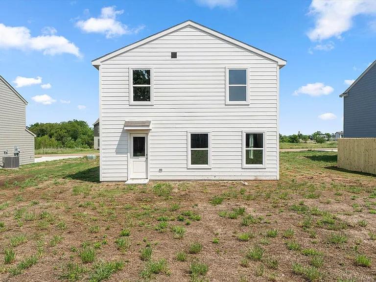 Rear exterior featuring white horizontal siding, a gabled roofline, and four windows