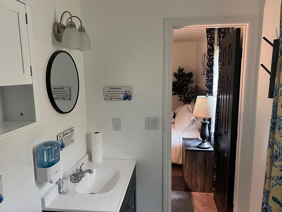 Clean bathroom vanity with storage, wall-mounted mirror and lighting, plus easy access to the adjacent bedroom.