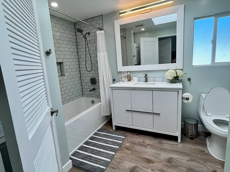 Bathroom with shower-bath combo.
Well-lit with natural light from sky-light, recessed and vanity lighting.