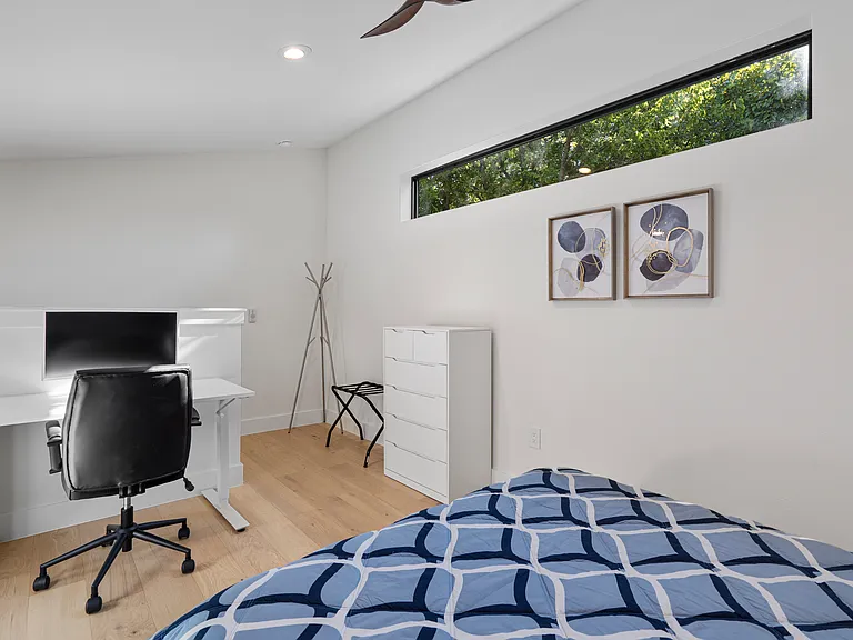 Loft with a standing desk, computer monitor, office chair and a queen bed with sealy posturepedic mattress.