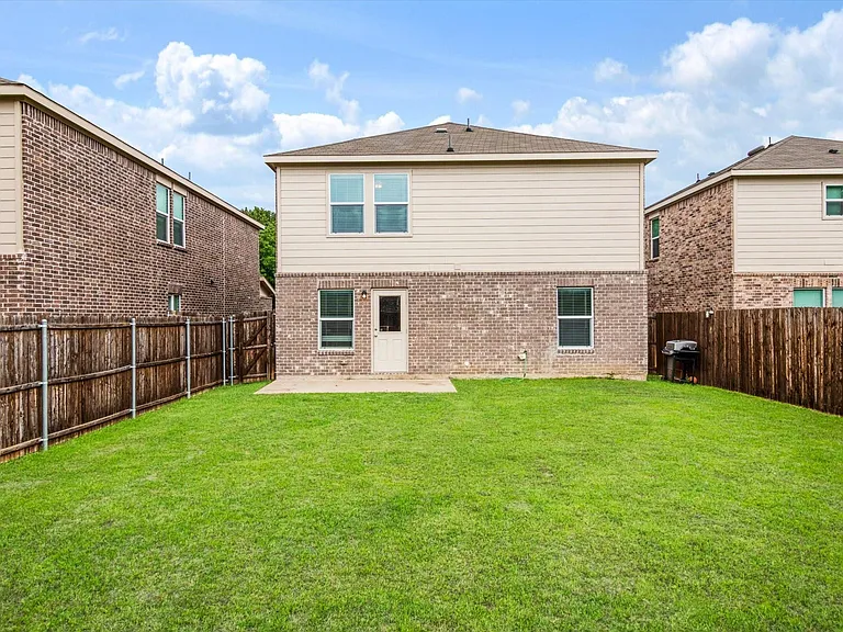 Spacious backyard featuring a lush lawn, privacy fencing, and a concrete patio