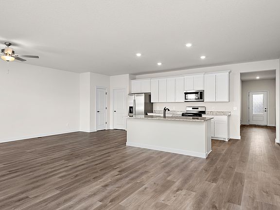 The kitchen has stainless steel appliances and plank flooring.