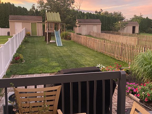Lovely fenced backyard with deck, play set, shed and many gardens.