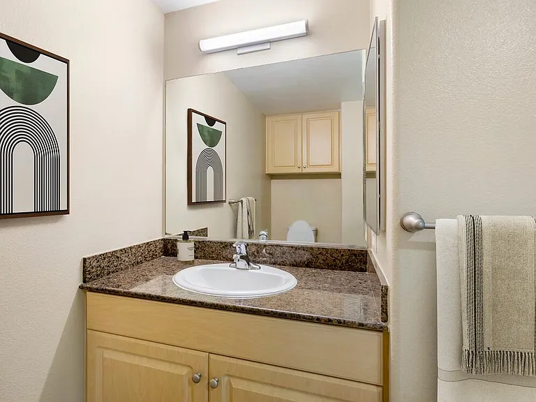 Renovated Package I bath with brown speckled granite, oak cabinetry, and hard surface flooring