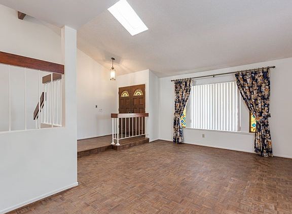 Living room w/ vaulted ceilings, skylight, & hardwood floors
