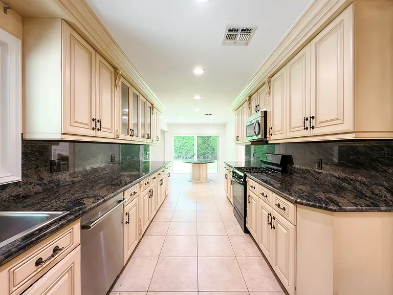 Full suite of stainless appliances lines this galley kitchen leading to a bright breakfast nook in a Beverly Hills luxury rental at 1094 Garden Lane, 90210.