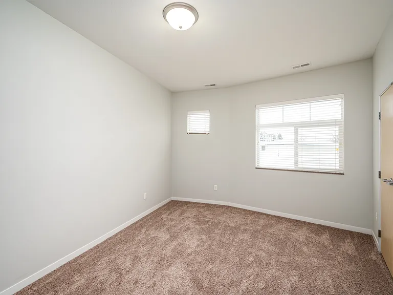 Bright and cozy room with plush carpeting, ample natural light from multiple windows, and neutral walls for a versatile living space. Bright and cozy room with plush carpeting, ample natural light from multiple windows, and neutral walls for a versatile l