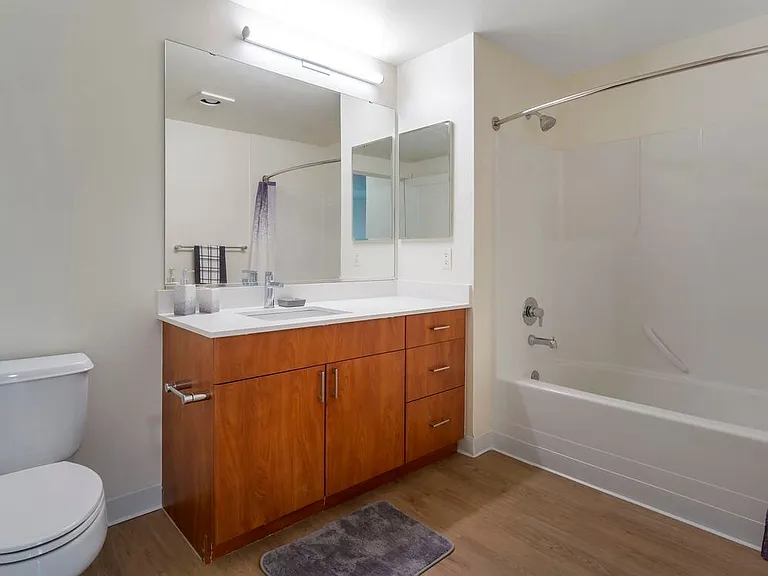 Renovated Package I bath with white quartz countertops, cherry cabinetry, and hard surface flooring