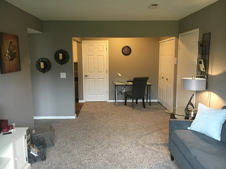 Open living and dining room with grey walls, tan carpet, and white six pannel doors.
