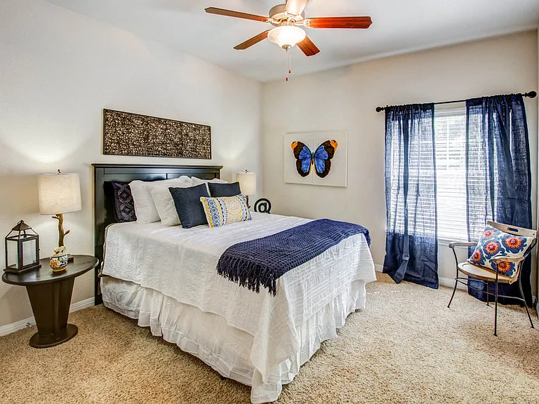 Bedroom with plush carpet, ceiling fan, and large window