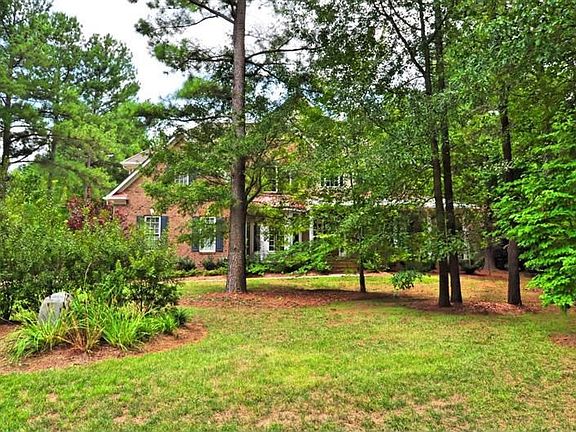Custom brick home sits well back from the road behind mature trees