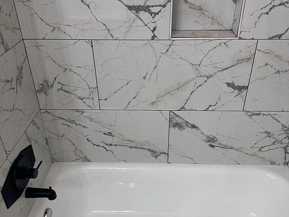 Tiled shower updated faucet features.