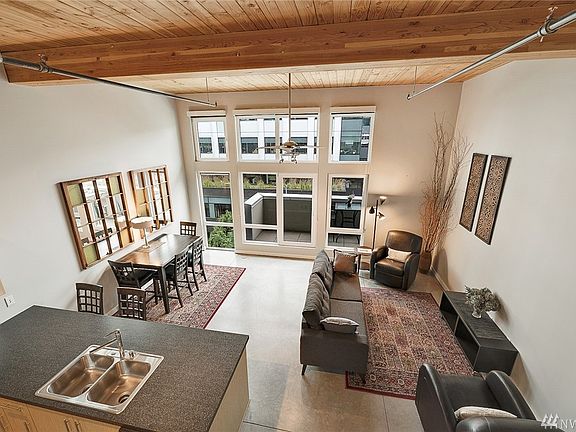 Morning light greets you through a wall of eastern-facing windows, almost 13' tall!  Turn door handle one-quarter turn and door opens. Turn handle one-half turn and door tilts inward, for fresh air.  Concrete floors, wood beam ceiling, private deck, and volume, volume, volume!